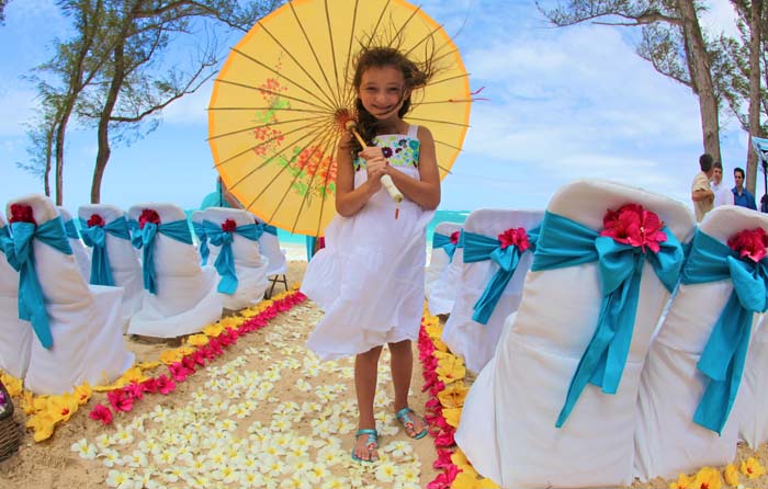 little gril holding umbrella at beach wedding